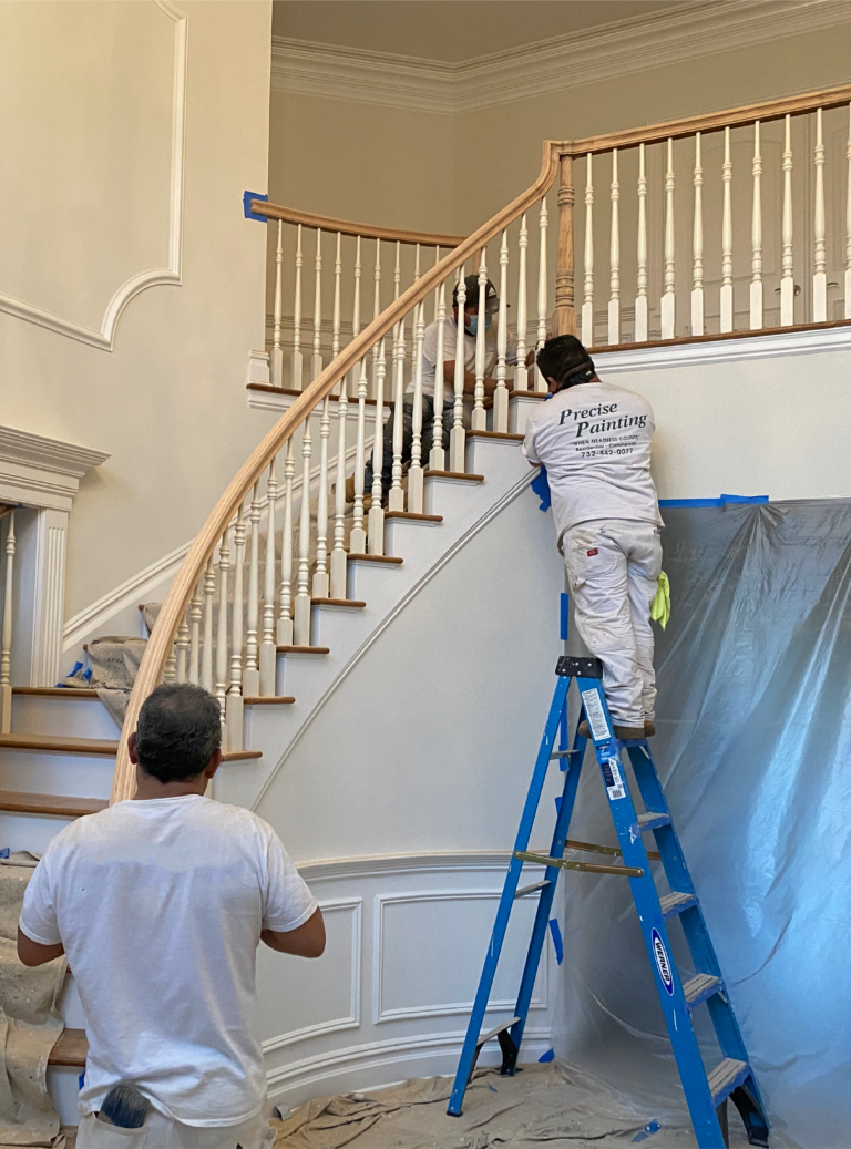 professional carpenters working on staircase railing refinishing